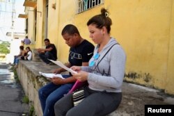 Migrantes cubanos chequean sus documentos mientras esperan para aplicar al asilo y el estatus de refugiado en México, Tapachula.