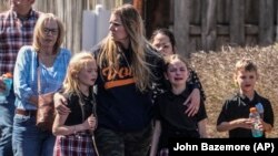 Varios niños y una mujer salen del centro de reunificación en la iglesia Bautista Woodmont después de un tiroteo en una escuela, el 27 de marzo de 2023, en Nashville, Tennessee. (AP Foto/John Bazemore)