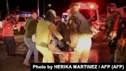 Oficial de la Policía transporta a un migrante lesionado durante incendio de albergue del INM en Ciudad Juárez, México (Photo by HERIKA MARTINEZ / AFP)