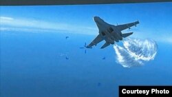 Esta foto tomada de un video divulgado el jueves 16 de marzo de 2023 muestra un Su-27 ruso acercándose a la parte trasera del dron MQ-9 y comenzando a liberar combustible a medida que pasa, sobre el Mar Negro, dijo el Pentágono. Cortesía: VOA.