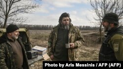 El soldado ucraniano Valera, de 61 años, habla con sus camaradas mientras permanecen en su posición cerca de Bajmut el 20 de marzo de 2023. (Aris Messinis/AFP).