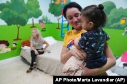 Isabel Benbow, migrante cubana, carga a Liam Tamayo, de 1 año, en la iglesia Rescate en Hialeah, Florida