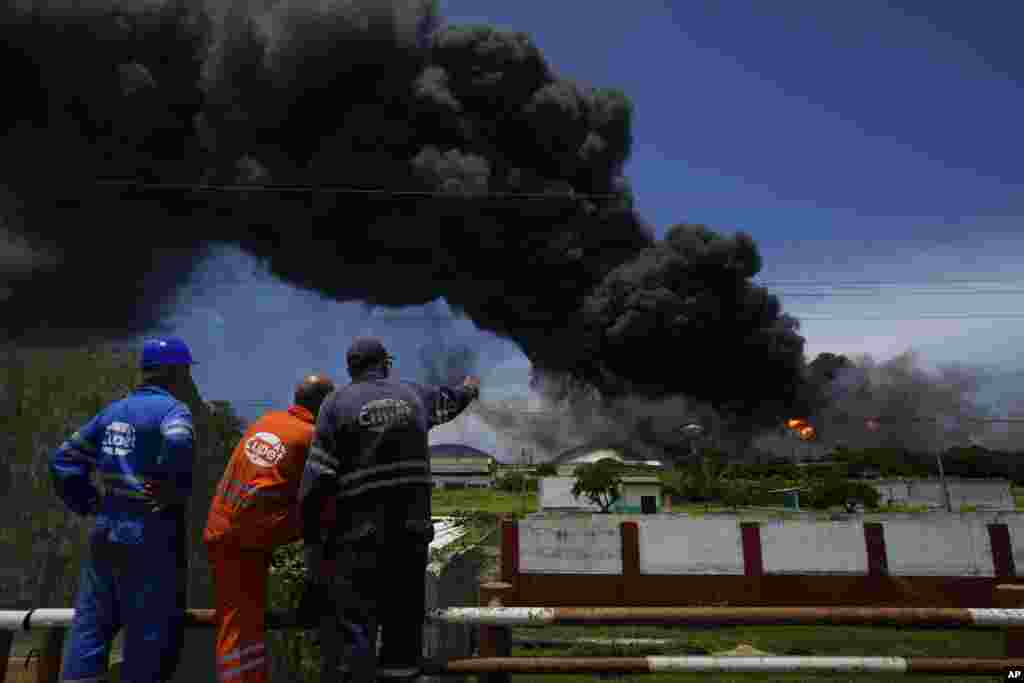 Trabajadores de Cuba Petróleo observan la larga columna de humo negro que se desprende del incendio en la base de supertanqueros de crudo, en Matanzas. (AP/Ramon Espinosa)