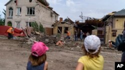 Niños observan a trabajadores que remueven los escombros tras un ataque con cohete a una vivienda en Kramatorsk, región de Donetsk, este de Ucrania.
(AP Foto/David Goldman).