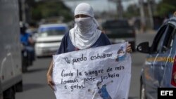 Una joven con la cara tapada y un cartel participa de un plantón contra el Gobierno de Nicaragua.