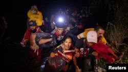 Cubanos llegan a suelo estadounidense después de vadear el río Grande desde México con cientos de otros migrantes, en Roma, Texas, el 9 de abril de 2022. (REUTERS/Adrees Latif)
