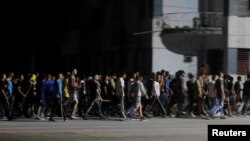 Agentes de civil con palos avanzan hacia los manifestantes de una protesta pacífica en La Habana, durante un apagón, el 30 de septiembre de 2022.