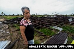 Maritza Carpio posa junto una casa de tabaco derribada por Ian en septiembre de 2022.