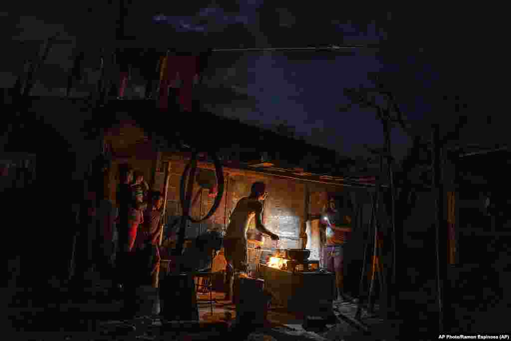 La familia Ramos prepara una coida en el fuego afuera de su casa dañada por el huracán Ian mientras continúa sin electricidad una semana después del paso del ciclón en La Coloma.