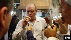 El ministro cubano de Inversión Extranjera, Rodrigo Malmierca (c), enciende un puro durante la inauguración de la feria comercial del XIV Festival del Habano, en La Habana.
