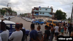 Cubanos observan dos hileras de carros patrulleros apostados cerca de la manifestación el 29 de septiembre.