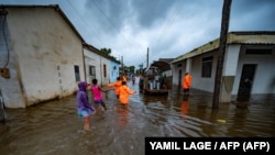 Niños caminan en el medio de la calle inundada después de que el huracán Ian pasara por el occidente de Cuba, el 27 de septiembre de 2022. (Yamil Lage/AFP).