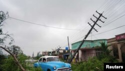 Un automóvil antiguo pasa por los escombros causados ​​por el huracán Ian a su paso en Pinar del Río, Cuba. 