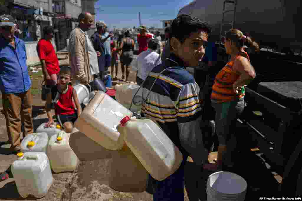 La gente hace fila en un camión cisterna que distribuye agua potable en medio de las secuelas del huracán Ian en La Coloma.