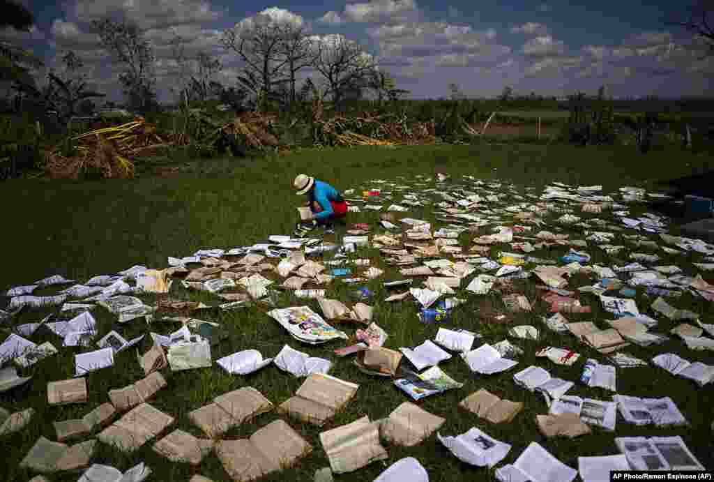 Una maestra seca libros de una escuela que resultó gravemente dañada por el huracán Ian en La Coloma.