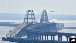 Un helicóptero arroja agua sobre el puente que conecta la península de Crimea con el territorio continental ruso sobre el estrecho de Kerch.