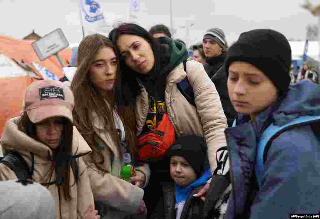 Un grupo de refugiados espera en una fila, tras huir de la guerra de la vecina Ucrania el martes 29 de marzo de 2022, en el paso fronterizo de Medyka, en el sureste de Polonia. (AP Foto/Sergei Grits