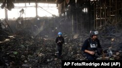 Periodistas entre los escombros de una infraestructura en Ucrania tras un ataque ruso, el 29 de marzo de 2022. (AP Photo/Rodrigo Abd).