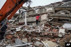 Un hombre busca sobrevivientes entre los escombros de un edificio, en Gaziantep, Turquía. (AP Foto/Mustafa Karali)