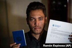 Marcos muestra el pasaporte cubano y el permiso para viajar a EEUU.