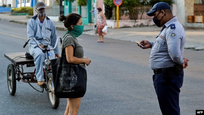 Un policía hace chequeos de peatones el sábado en el barrio El Carmelo, que el gobierno anunció inicialmente que iba a aislar y luego mantuvo abierto por temor a que se hiciera aún más difícil el acceso a provisiones, según reporta el diario 14ymedio (Foto: Yamil Lage/AFP).