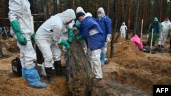 Investigadores extraen cadávares de más de 400 tumbas en la zona de Izyum, Ucrania.