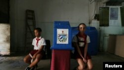 Dos niños custodian la urna en un colegio electoral de La Habana durante el referendo constitucional, el 24 de febrero de 2019. (Reuters/Fernando Medina).