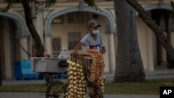 Un hombre con una mascarilla protectora vende ajos y cebollas en La Habana en medio del rebrote de coronavirus. (AP/Ismael Francisco)