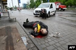 Un hombre llora junto al cadáver de otro, víctima durante bombardeo ruso a la ciudad de Kharkiv, en el este de Ucrania