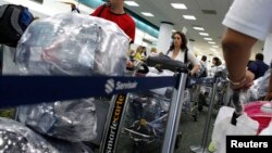 Cubanos residentes en EEUU cargados de equipaje hacen fila en el Aeropuerto Internacional de Miami para viajar a la isla. REUTERS/Carlos Barria/Archivo