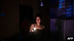Una joven sostiene una vela en medio del apagón, en La Habana, Cuba. (YAMIL LAGE / AFP)