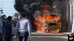 Un policía observa como se incendia un ómnibus en plena calle Belascoaín en La Habana.