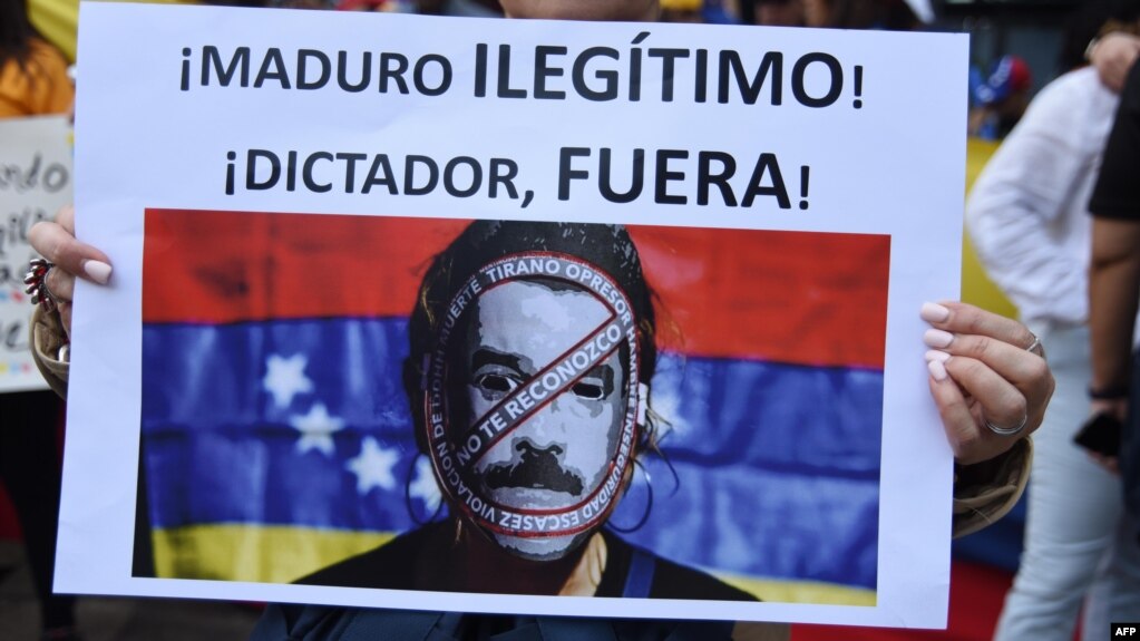 Manifestante muestra pancarta calificando de dictador a Maduro