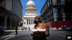 Una mujer carga un cartón de huevos cerca del Capitolio, en La Habana. La capital cubana no se incorporará aún a la primera etapa de normalización. (AP/Ramón Espinosa)