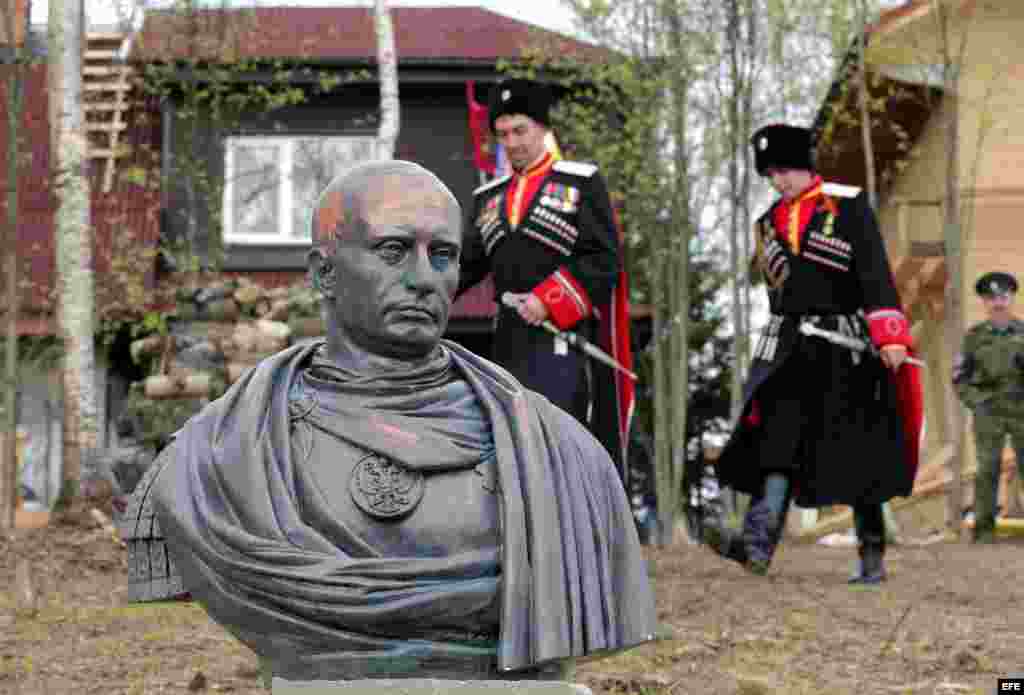 Cosacos rusos con su uniforme posan junto a busto de Putin.