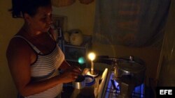 Una mujer prepara la comida en la cocina, iluminada con velas, durante un apagón en el barrio de Alamar