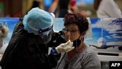 Una pasajera es examinada por coronavirus en el aeropuerto de La Habana. (YAMIL LAGE / AFP)