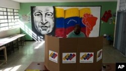 Al fondo imagen de Hugo Chávez, mientras un hombre emite su voto durante las elecciones regionales en un colegio electoral en Caracas, Venezuela, el domingo 21 de noviembre de 2021.