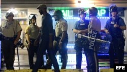 Policías y manifestantes en Ferguson, Misuri, tras el toque de queda.