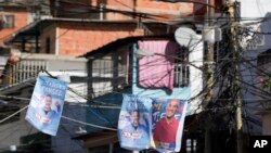 Carteles de candidatos del partido en el gobierno, Miranda Héctor Rodríguez, a la derecha, y del aspirante a la alcaldía de Sucre, José Vicente Rangel, colgados en una calle en Caracas. (AP/Ariana Cubillos)