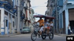 Turistas pasean en bicitaxi en una calle de La Habana.