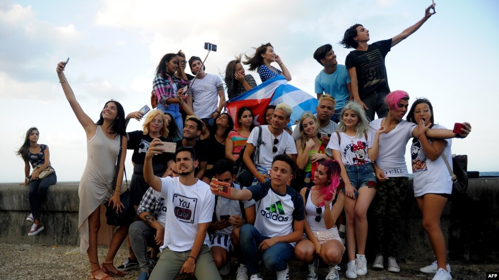 Jóvenes cubanos se toman selfies en el Malecón. YAMIL LAGE / AFP