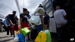 Migrantes de Venezuela abordan un autobús al Aeropuerto Internacional de Tocumen en Ciudad de Panamá, el miércoles 26 de octubre de 2022. (AP Foto/Arnulfo Franco).