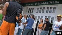 Varias personas hacen colas en un Banco de La Habana.