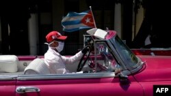Un taxista privado transporta turistas por La Habana portando una máscara protectora por el coronavirus.