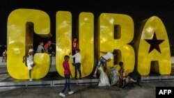 Niños juegan en un gran cartel con la palabra Cuba a lo largo del malecón santiaguero. (Archivo)