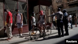 Un policía organiza una fila para comprar alimentos en medio de las nuevas medidas de control en La Habana por el rebrote de COVID-19. (REUTERS/Alexandre Meneghini)