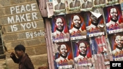 Una mujer keniana pasa junto a un grafiti que dice "El pacificador eres tú", en el suburbio de Kibera en Nairobi, Kenia.