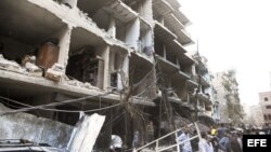Fotografía cedida por la agencia de noticias SANA que muestra a unos ciudadanos sirios en el lugar donde se registró la explosión de un coche bomba en el barrio de Def al Shuk en Damasco, Siria.