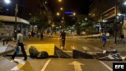 Un grupo personas preparan una barricada en una calle de Caracas. Archivo.